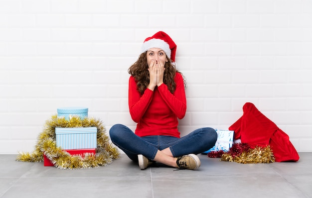 Foto chica en vacaciones de navidad sentados en el suelo con expresión facial sorpresa