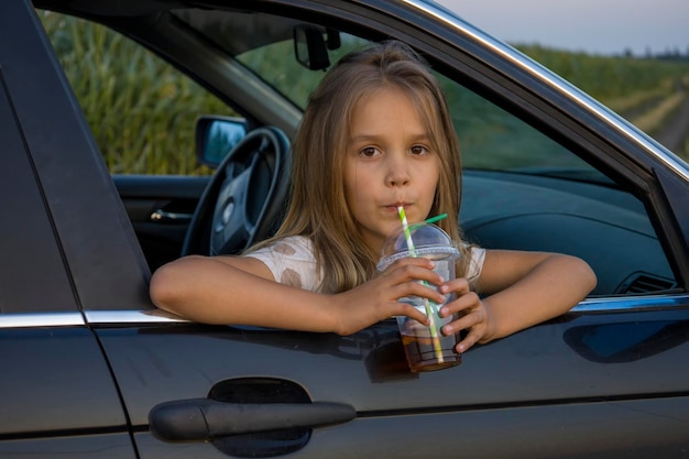 Una chica con un vaso de plástico de un cóctel en un auto.