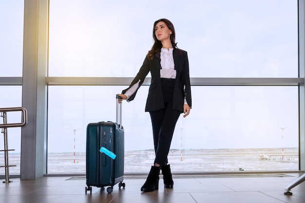 Chica en la ventana del aeropuerto espera un vuelo