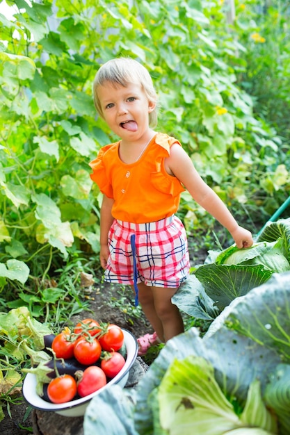 Chica con verduras de cosecha en el jardín