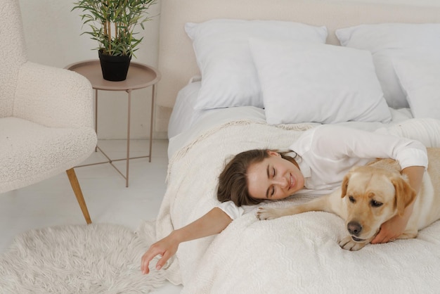 Chica vestida de blanco con perro labrador jugando en casa