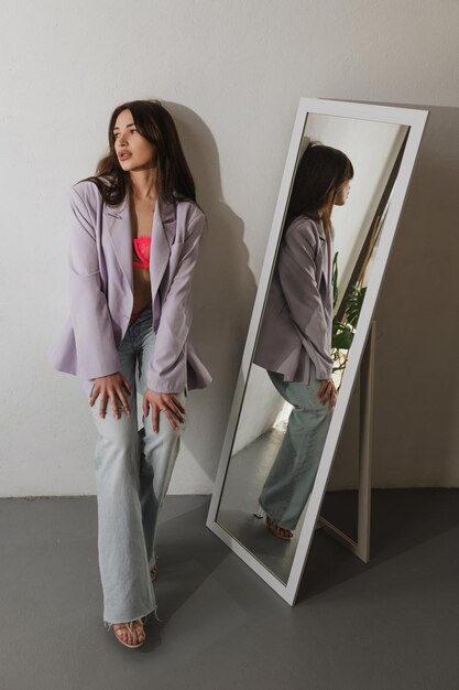 Chica vestida cerca del espejo posa para un fotógrafo