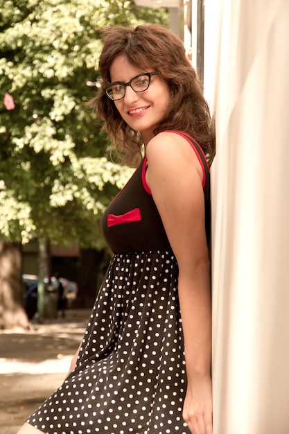 Una chica vestida de estilo vintage apoyado en una pared y esperando.