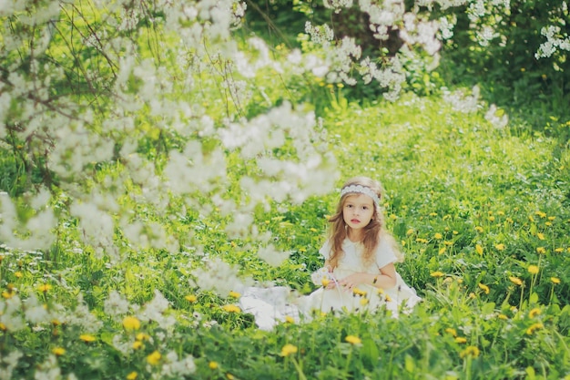 Chica vestida sentada en el jardín de cerezos de primavera