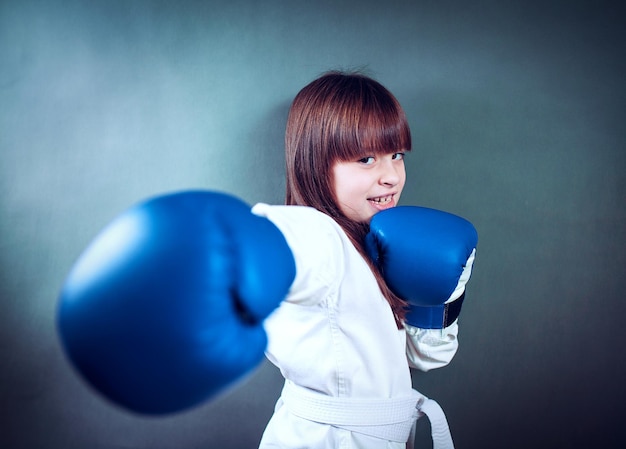 Chica vestida con un uniforme de karate y un guante de boxeo azul