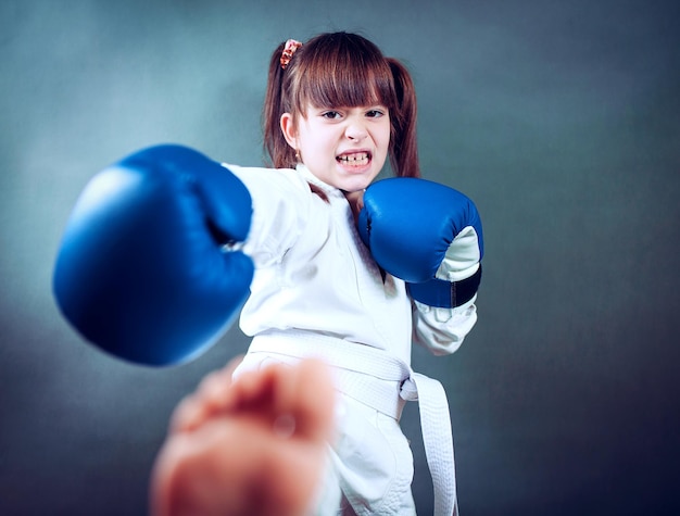 Chica vestida con un uniforme de karate y un guante de boxeo azul