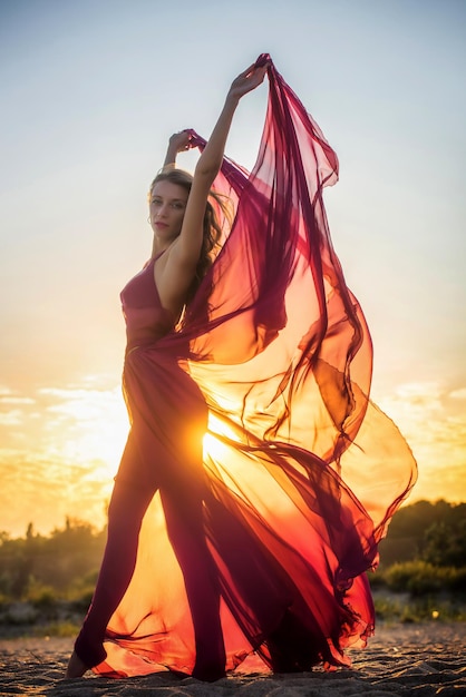 Chica en vestido aireado posando al atardecer