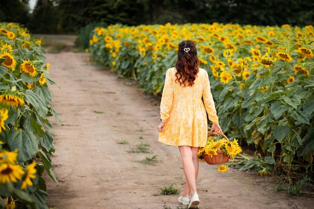 Una chica con un vestido amarillo camina en un campo de girasoles.