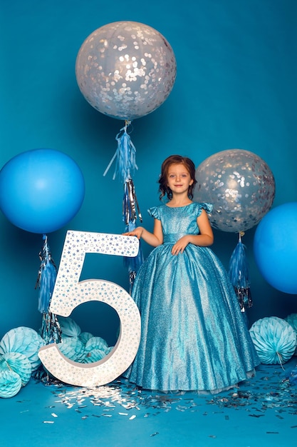 La chica con el vestido azul en el estudio con el globo y con el número cinco