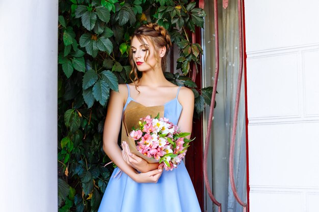 Chica en vestido azul con ramo de flores en la calle