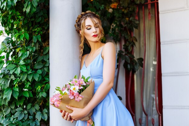 Chica en vestido azul con ramo de flores en la calle