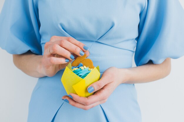 Chica con un vestido azul tiene un cupcake