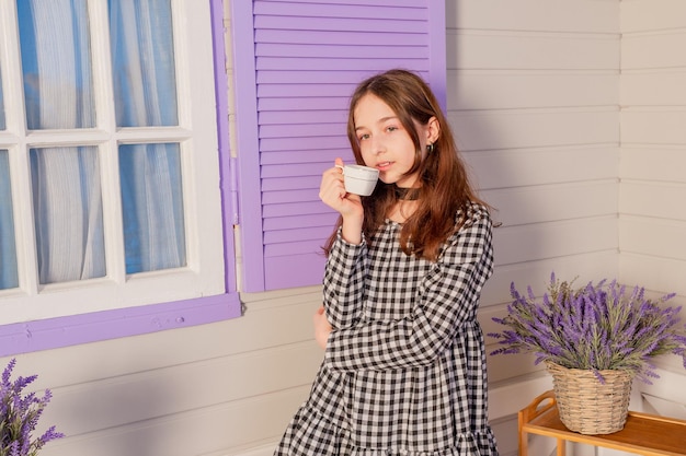 Una chica con vestido bebe té Un adolescente en casa