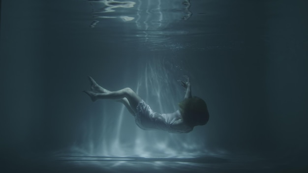 Foto una chica con un vestido blanco cae bajo el agua.