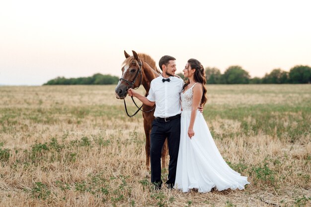 Una chica con un vestido blanco y un chico con una camisa blanca en un paseo con caballos marrones en el pueblo