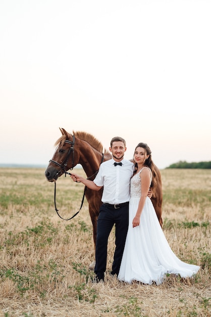 Una chica con un vestido blanco y un chico con una camisa blanca en un paseo con caballos marrones en el pueblo