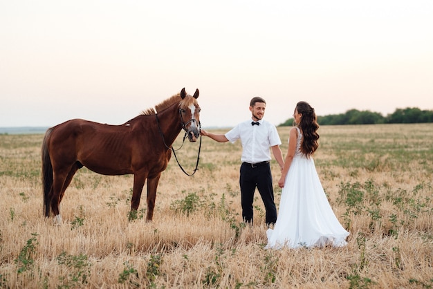 Una chica con un vestido blanco y un chico con una camisa blanca en un paseo con caballos marrones en el pueblo