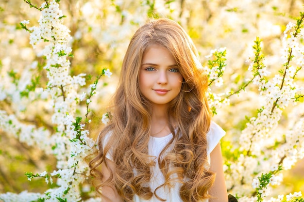 Una chica con un vestido blanco se encuentra en un jardín con flores.