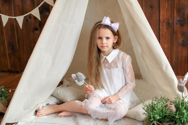 Una chica con un vestido blanco está sentada en una tienda de campaña