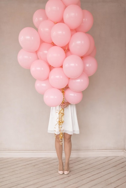 Una chica con un vestido blanco con globos rosas.