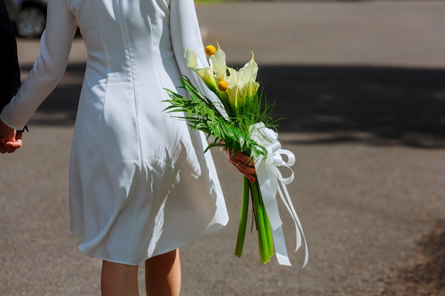 Chica en vestido blanco con un ramo de flores y verde contra.