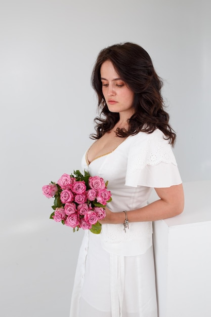 Chica con un vestido blanco con un ramo de flores.