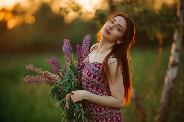 Chica con un vestido de color. Sostiene flores en sus manos