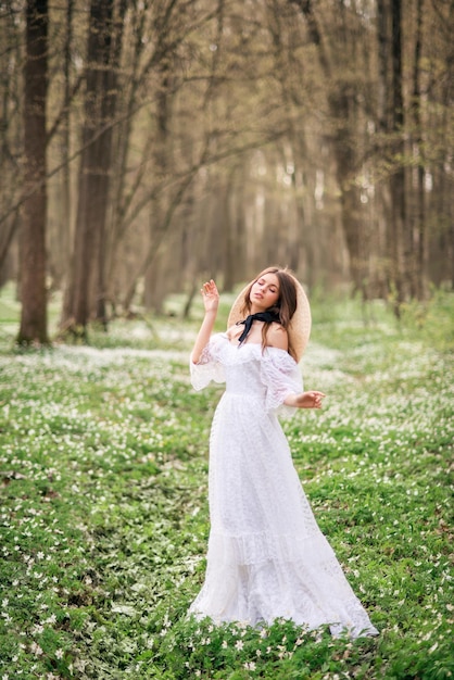 Chica con un vestido largo blanco en un bosque de primavera Ninfa del bosque