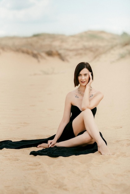Chica con un vestido largo negro en un desierto de arena