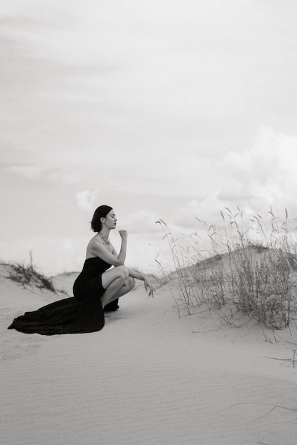 Chica con un vestido largo negro en un desierto de arena