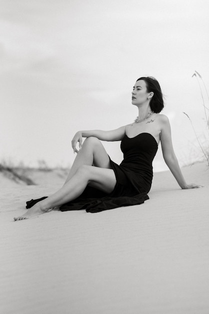 Chica con un vestido largo negro en un desierto de arena