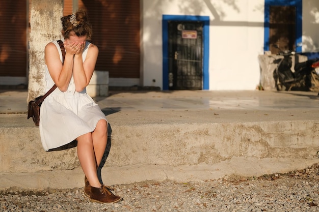 Chica con un vestido ligero de verano está llorando en la calle