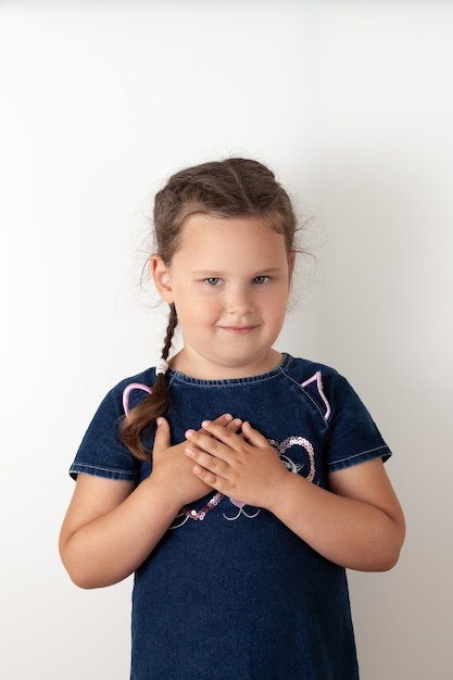 La chica del vestido de mezclilla azul se llevó las manos al pecho, dando las gracias o rezando. Niño sonriente, aislado