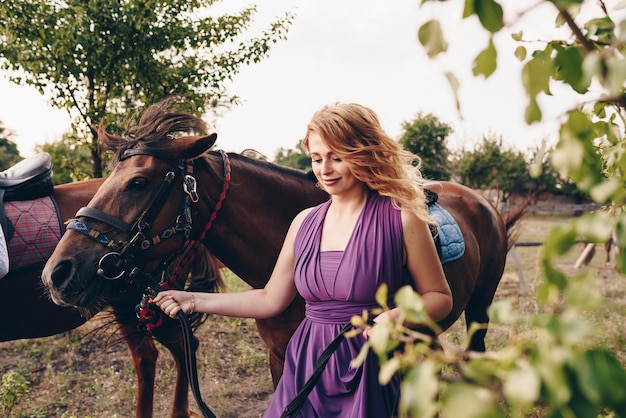 Foto una chica con un vestido morado en un paseo con un caballo.