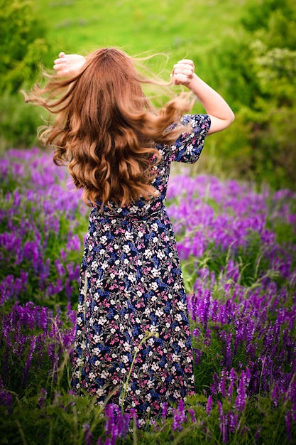 Una chica con un vestido morado sobre un fondo de flores azules.