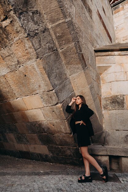 Chica en vestido negro caminando en la ciudad vieja