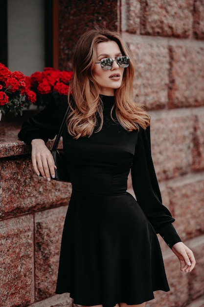 Chica en vestido negro y flores rojas.