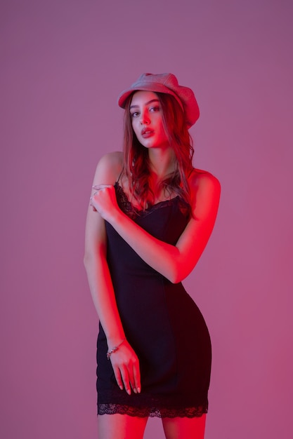 Chica con un vestido negro y una gorra gris. Hermosa joven con cabello castaño rizado. retrato