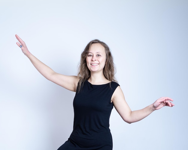 Foto chica con vestido negro y maquillaje natural mantiene el equilibrio y sonríe