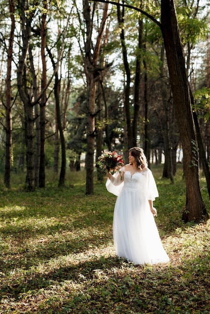 Chica en un vestido de novia en el bosque de otoño con el telón de fondo de árboles silvestres