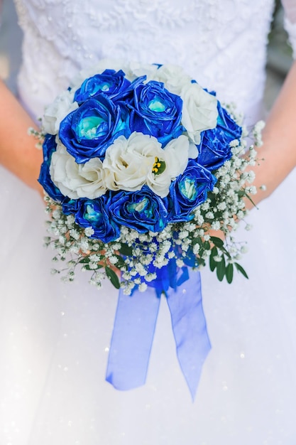 Foto una chica con un vestido de novia sostiene un ramo de rosas blancas y azules con una vista recta de primer plano