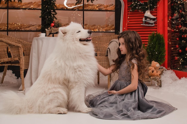 Una chica con un vestido con un perro samoyedo. Concepto de año nuevo