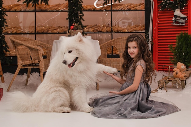 Una chica con un vestido con un perro samoyedo. Concepto de año nuevo