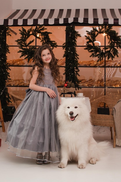 Una chica con un vestido con un perro samoyedo. Concepto de año nuevo