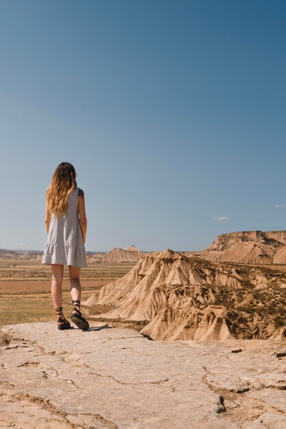 Chica con vestido de pie en el desierto de las Bardenas Reales de Navarra en verano