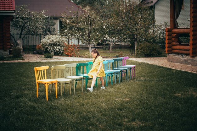 Una chica con un vestido que pasa junto a una línea de sillas de colores un concepto de una fiesta en casa o un ho ...