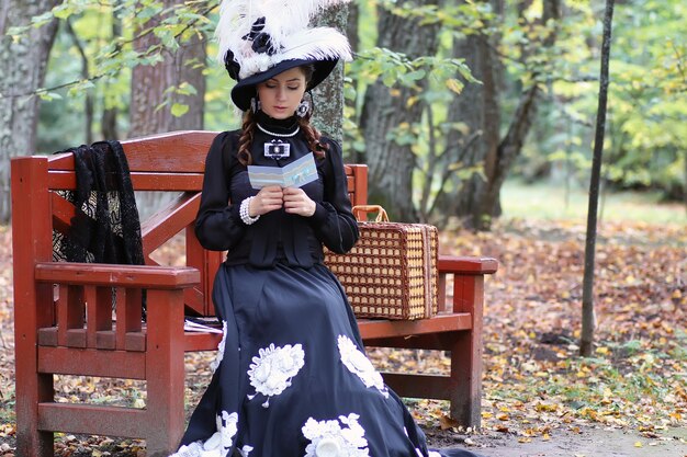 Chica en vestido retro del siglo pasado leer carta en el banquillo