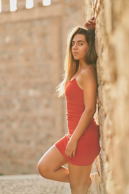 Chica con vestido rojo ajustado y pelo largo y lacio posando en Toledo