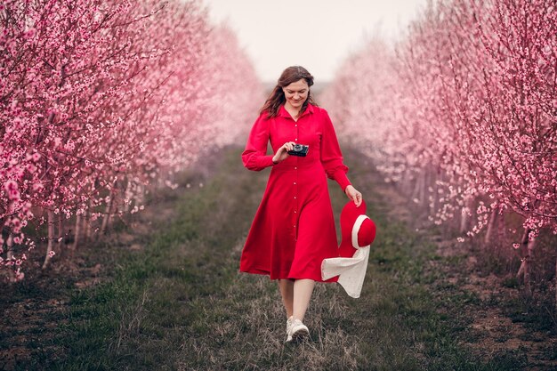 Una chica con un vestido rojo camina en el jardín con el perro Lady in red