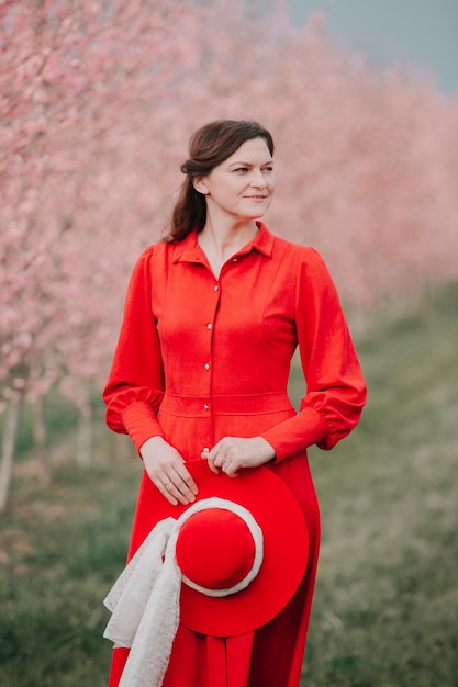 Una chica con un vestido rojo camina en el jardín de primavera.